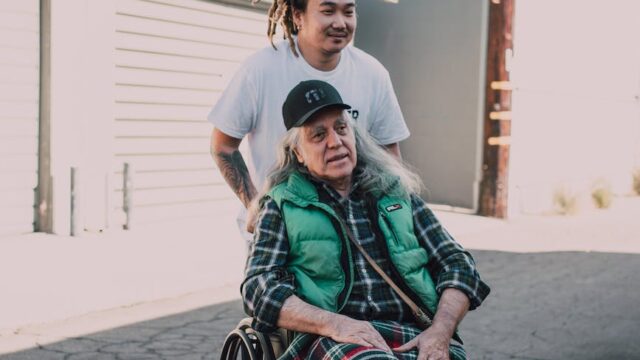 man pushing an elderly man on a black wheelchair